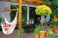 A summer terrace with a hammock and mixed plants in containers