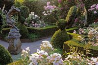 Stone statue in formal rose garden with Buxus topiary