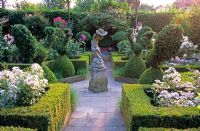 Stone statue in formal rose garden with Buxus topiary 