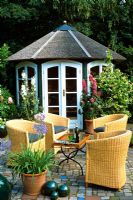 Rattan chairs and table on patio infront of summerhouse