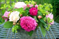 Rose arrangement with Achemilla mollis in old metal bucket - Rosa 'Madame Isaac Periere' and Rosa 'Heritage' in foreground