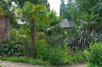 Hot and exotic borders with summerhouse