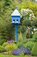 Blue wooden birdhouse in small country garden