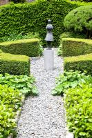 Formal garden with gravel paths and central figurative sculpture 