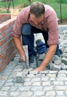 Constructing raised vegetable beds and cobbled path - Man laying cobbles