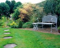 Bench by hedge and Stipa, hexagonal stepping stones in lawn