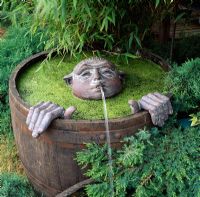 Half barrel water feature with submerged bronze head waterspout and hands
