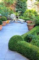 Paved patio with reclining chair and clipped Buxus hedging