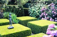 Formal garden with clipped Buxus shapes and small figurative statue