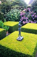 Sculpture in formal garden with clipped Buxus squares