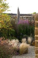 View into dry garden with Stipa tenuissima and driftwood sculpture in background