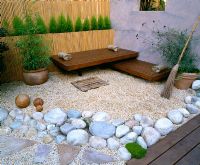 Roof garden with bamboo fence, white boulders, Red Cedar deck and seats, rendered wall with window and besom broom