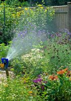 Sprinkler being used to water flower beds