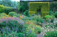 Flower garden including Knautia macedonica 'Lawley's Pink', Tradescantia, Geranium, Polemoniums, Eryngiums and Buxus topiary - Herterton House, nr Cambo, Morpeth, Northumberland.
