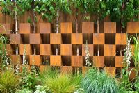 Betula trees growing through a wall created from alternating corten steel boxes with planting of mixed grasses and perennials including digitalis and hostas - Garden - The Pemberton Greenish Recess Garden, Designer - Paul Hensey with Knoll Gardens, Sponsor - Pemberton Greenish