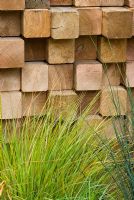 Grasses planted in front of a wall created from irregular wooden blocks - Garden - The Pemberton Greenish Recess Garden, Designer - Paul Hensey with Knoll Gardens, Sponsor - Pemberton Greenish