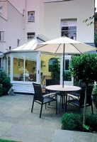 Small urban garden with table, chairs and parasol on paved area