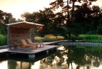 Wooden deck with sun loungers beside swimming pond - Sweden