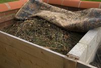 Organic compost in purpose built bay with old rug for covering