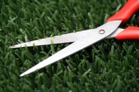 Scissors cutting plastic astroturf lawn