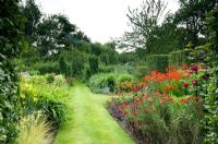 Summer garden with grass path and hot coloured border of Dahlias, Roses, Crocosmia and Achillea - Devils End Haddiscoe, Norfolk