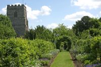 Formal borders leading to archway and church - Cranborne Manor Gardens