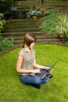 Lady sitting on lawn using laptop computer