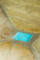 Decorative turquoise glazed tile inset into stone paving