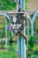Verdigris colonnade with head of the green man in the Mediaeval Herb Garden, The Abbey House, Wiltshire