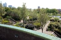 Mile End Park, East London with view to Canary Wharf office towers - Water fountain and pool with beds planted with Bamboo, Cortaderia, Rosemary, Euphorbia and Eanothus