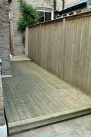 Area of decking down the side of a terraced town house that has been cleaned using a pressure washer.