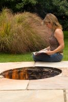 Clare Matthews sits beside the firepit on her patio in her Devon garden