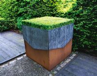Lead and rusty metal container planted with Buxus - Ridler's Garden, Swansea, Wales