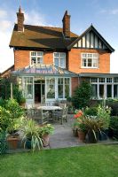 House with conservatory and patio dining area. Containers with Laurus nobilis,  Lavandula, Phormium, Lilium and Hosta - Villa Ramsdal, Chelmsford, Essex