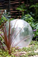 Glass ball water feature with Phormium. Garden - The Way Forward, Designers - Zoe Cain, with Jim Buttress VMH and Jocelyn Armitage, for St Joseph's Hospice and Perennial Gardeners' Royal Benevolent Fund