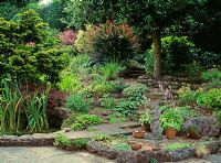 Small garden with decorative birdbath, hard landscaping, Hosta, Berberis, and Hebe