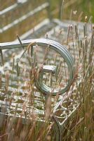 Shabby chic pale blue metal bench detail with wild grasses