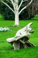 Wooden carved bench on lawn with Betula utilis var jacquemontii behind - Woodpeckers, Warwickshire