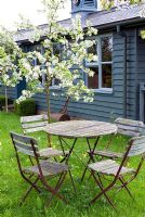 Old cafe style table and chairs in Spring orchard with blossom and wild flowers