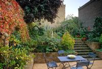 Urban garden on different levels with cafe style table and chairs on decked patio - London
