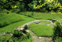 Edwin Lutyens designed stone steps amongst long grass and wild meadow - Great Dixter