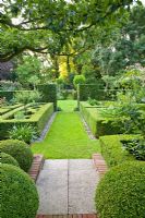 Formal country garden with grass paths, low evergreen hedging and trees