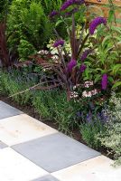 Grey and white square paving with border containing Buddleia, Lavandula and Phormium in the 'On the Square' garden, Provincial Grand Lodge of Cheshire Freemasons - RHS Tatton Flower Show 2008