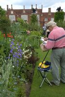 Artist painting the herbaceous borders of the walled garden at Helmingham Hall, Suffolk