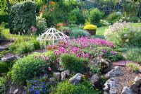Mixed rockery bed with Armeria, cloche in background