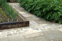 Recycled old slabs, sets and broken slabs to create hard paths around raised beds with wheelchair access in mind