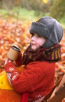 Child wrapped up warm with mug of spiced apple juice