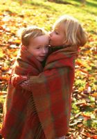 Children keeping warm wrapped in blanket in the woods