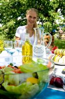 Woman sat beside table of food in garden