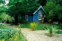 Blue painted summer house under trees with gravel garden - Barleywood, Hampshire.